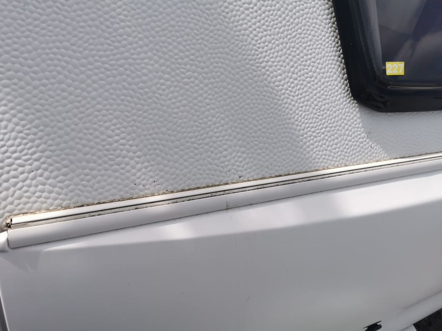 Mørk misfarvning langs en aluminiumsliste under et vindue udvendigt på en campingvogn